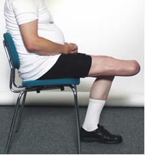 Person med et underben amputeret sidder på en stol og strækker benet frem
