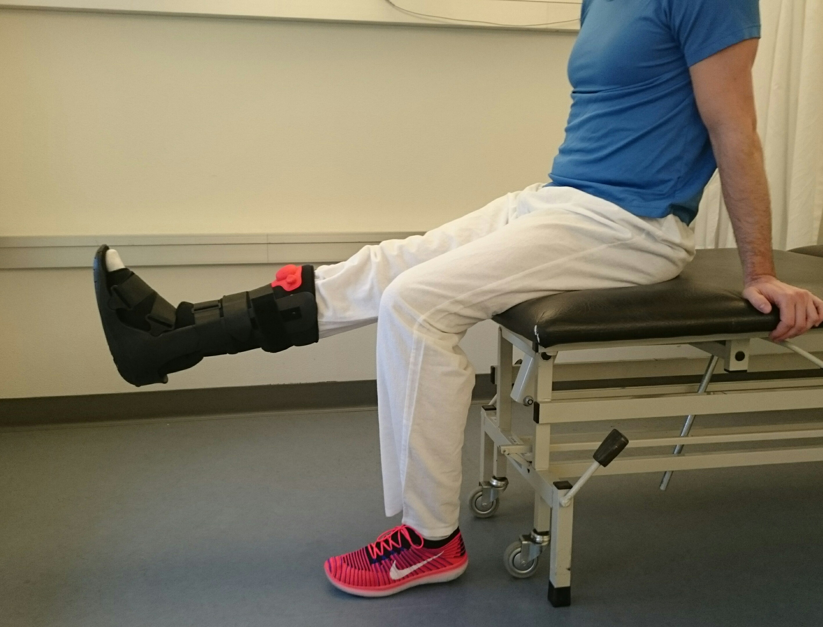 Siddende person strækker i knæet på et ben med fodbandage