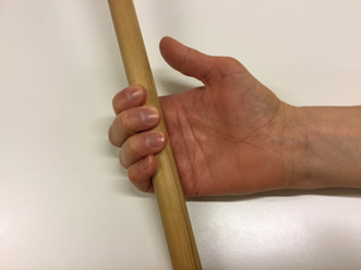 Hånd, hvor fingrene holder omkring en pind med de yderste led af fingrene