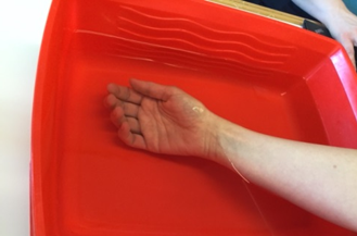 Hånd i balje med vand, hvor håndfladen vender op ad