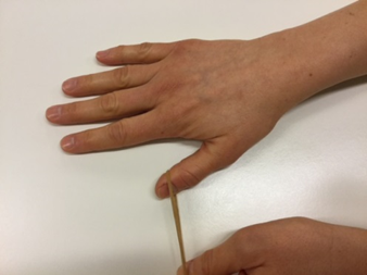 En hånd, hvor tommelfingeren trækker i en elastik med det yderste af fingeren