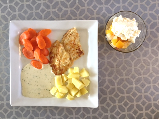 Tallerken med fiskefiletter, kartoffeltern, skiver af gulerod, persillesoves og skål med henkogt frugt og råcreme