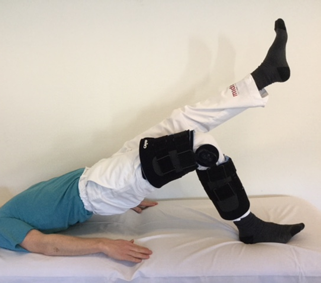 Person med hængselbandage  på knæet laver bækkenløft med det raske ben strakt op