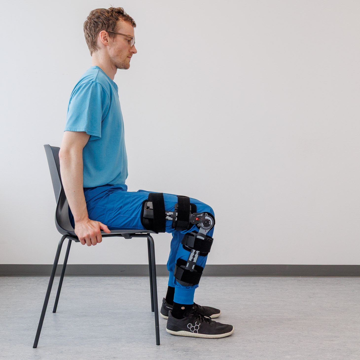 Mand med bandage sidder med begge fødder i gulvet