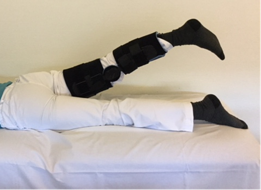 Person med hængselbandage på knæet ligger på maven og løfter benet bagud
