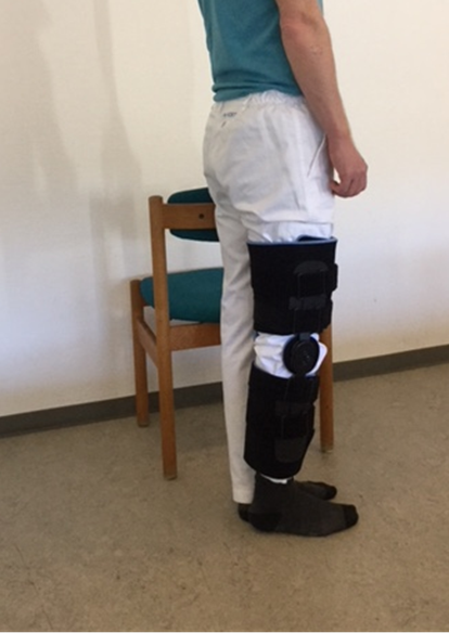 Person med hængselbandage står op med støtte til stol