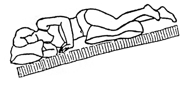 Person ligger på siden på underlag som hælder 45 grader ved hovedgærde. Der er puden mellem knær og under hovede.