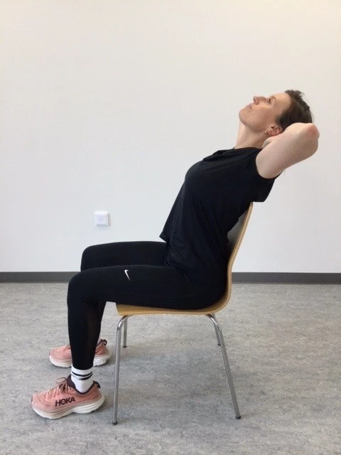 Kvinde sidder på stol og læner sig bagud 