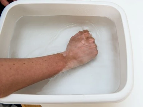 Hånd varmes op i balje med vand