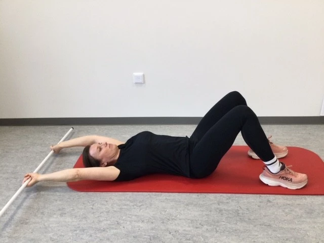 Kvinder ligger på gulvet med pind i strakte hænder over hovedet