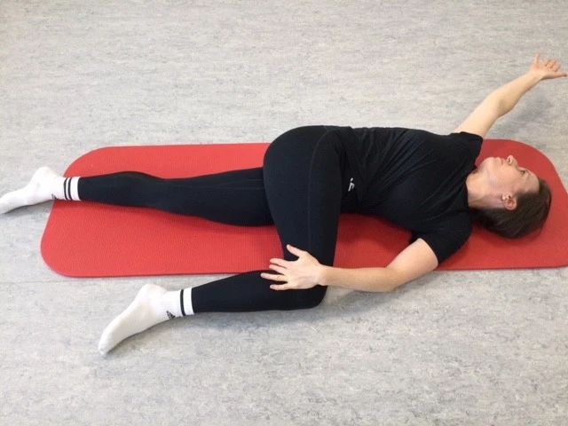 Kvinde ligger på ryggen og roterer overkroppen