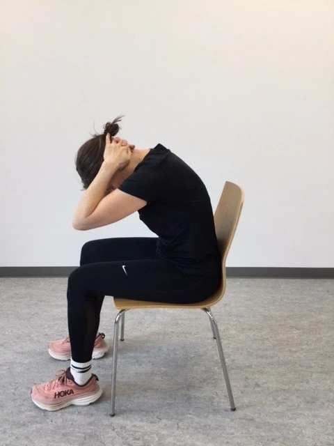 Kvinde sidder på stol og læner sig fremover