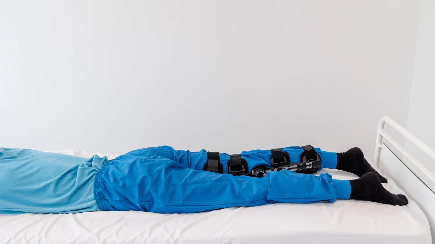 Person ligger på maven med hængselbandage på knæ