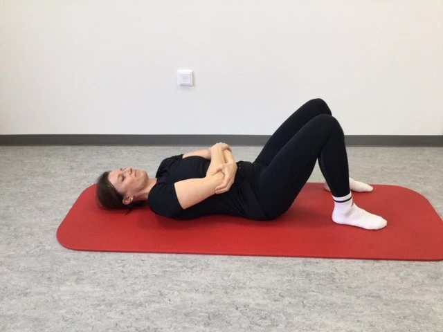 Kvinde ligger med armene foldet over maven