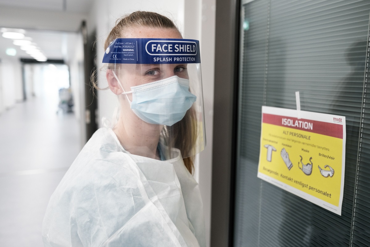 Sygeplejersker iført engangskittel, visir og mundbind er på vej ind på en isolationsstue.