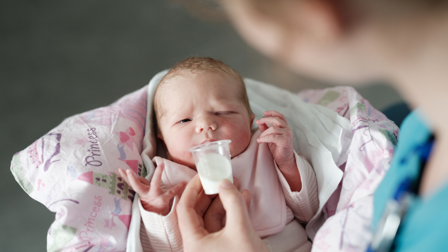 Baby får mælk i kop