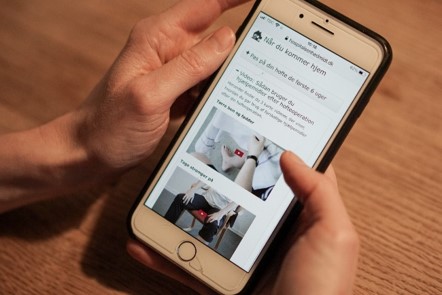 Foto af sengeafsnittets patientvejledninger der vises p&aring; en mobiltelefon