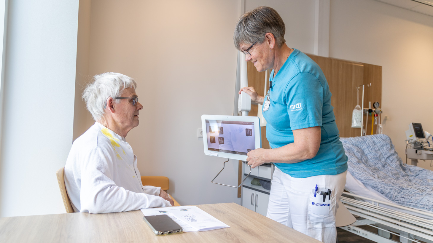 Personale viser tablet til patient på Øre, Næse og Hals sengeafsnit