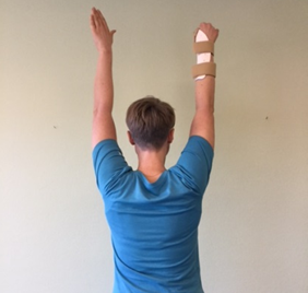 Person med skinne på tommelfingeren, strækker begge arme op i luften