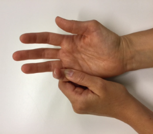 Den ene hånd holder omkring anden hånds lillefingers grundled, mens lillefingeren bøjer i mellemleddet